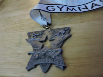 GYMNASTIC SILVER COLORED 2.5 X 2.5 INCH MEDAL WITH WHITE GYMNASTICS RIBBON