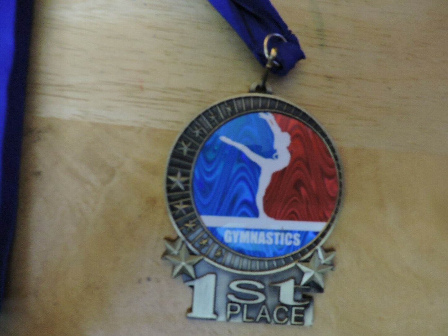 GYMNASTIC GOLD  COLORED 2.5 X 3.5 INCH MEDAL WITH BLUE RIBBON 1ST PLACE