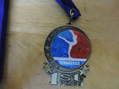 GYMNASTIC GOLD  COLORED 2.5 X 3.5 INCH MEDAL WITH BLUE RIBBON 1ST PLACE