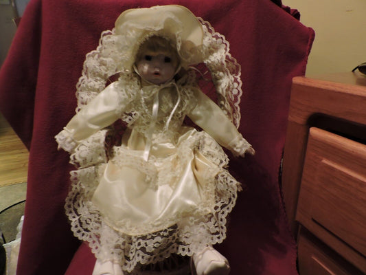 BRINN PORCELAIN DOLL SITTING IN WICKER CHAIR